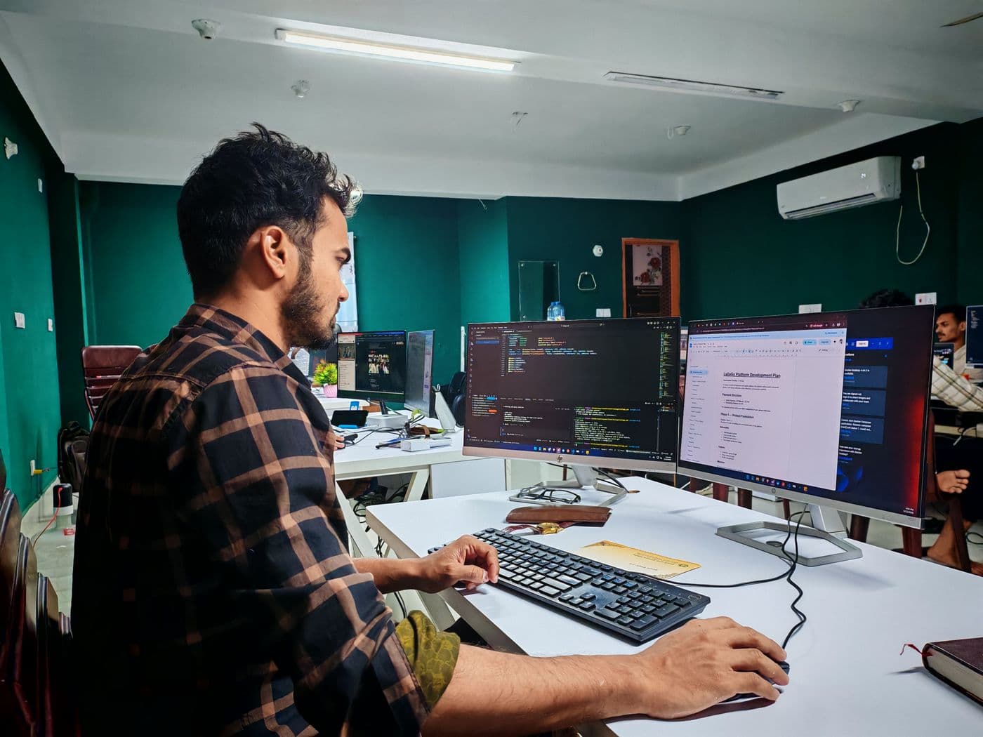 Developer writing code across two monitors