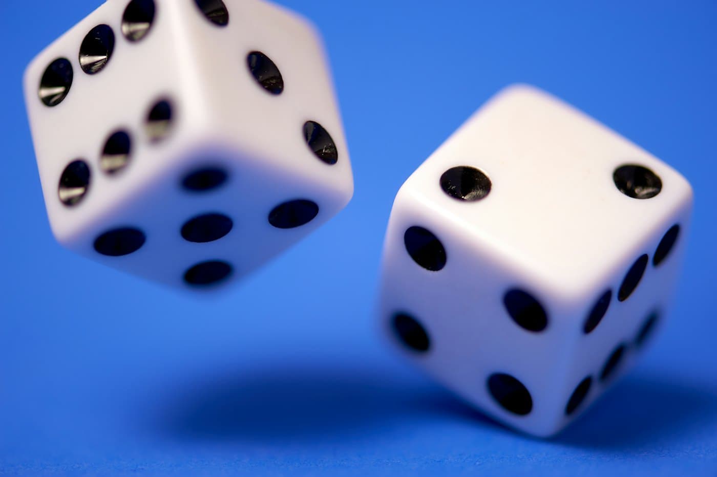 Two white dice falling against a bright blue background