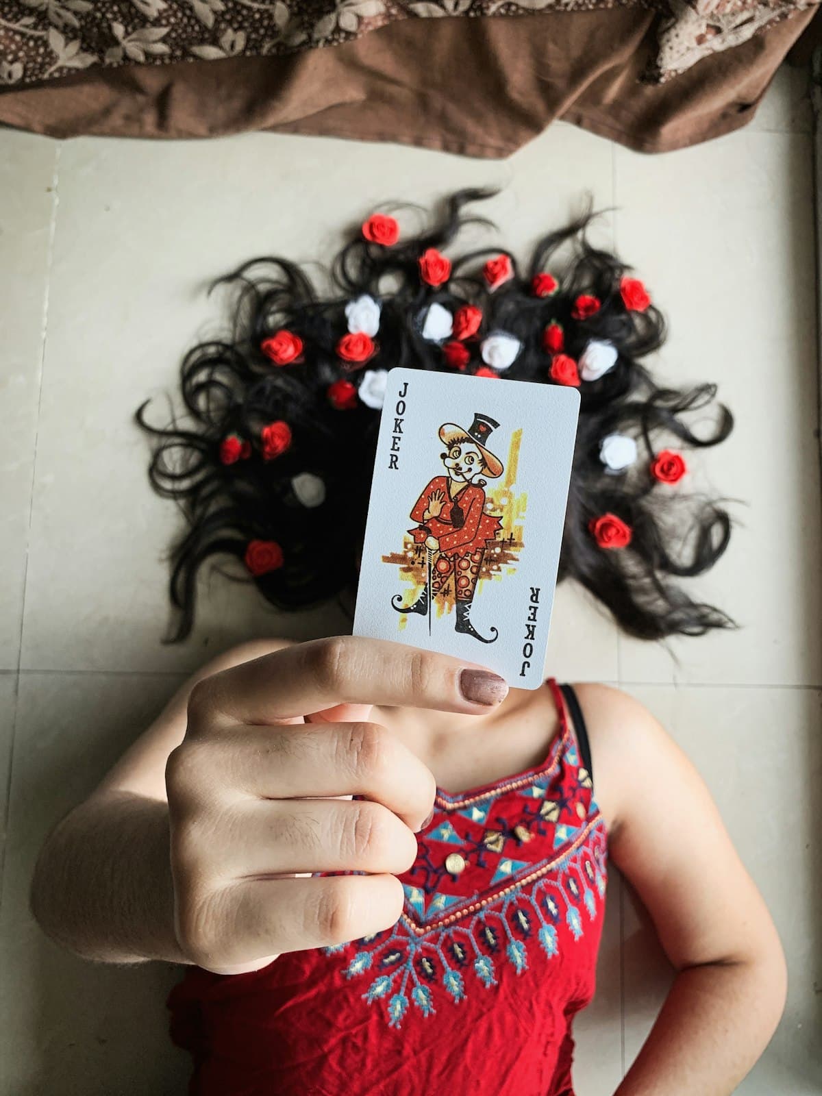 Woman in a red dress holding up a joker playing card