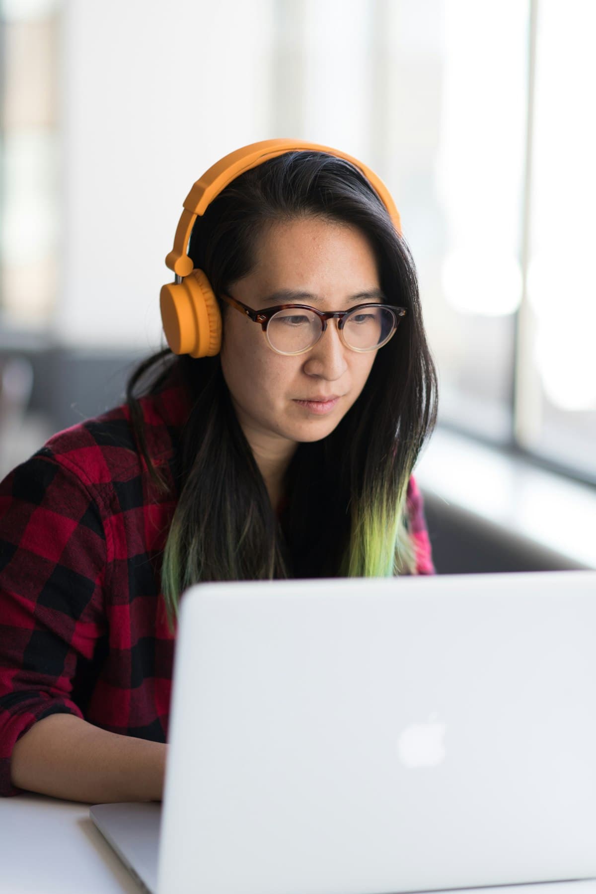 Engineer wearing yellow headphones working on a laptop