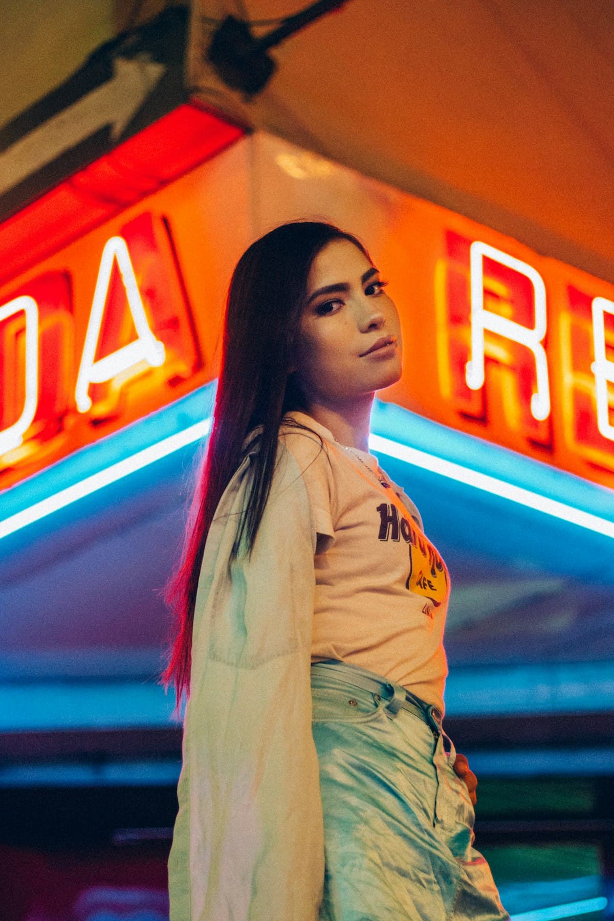 Woman standing under bright neon signs at night