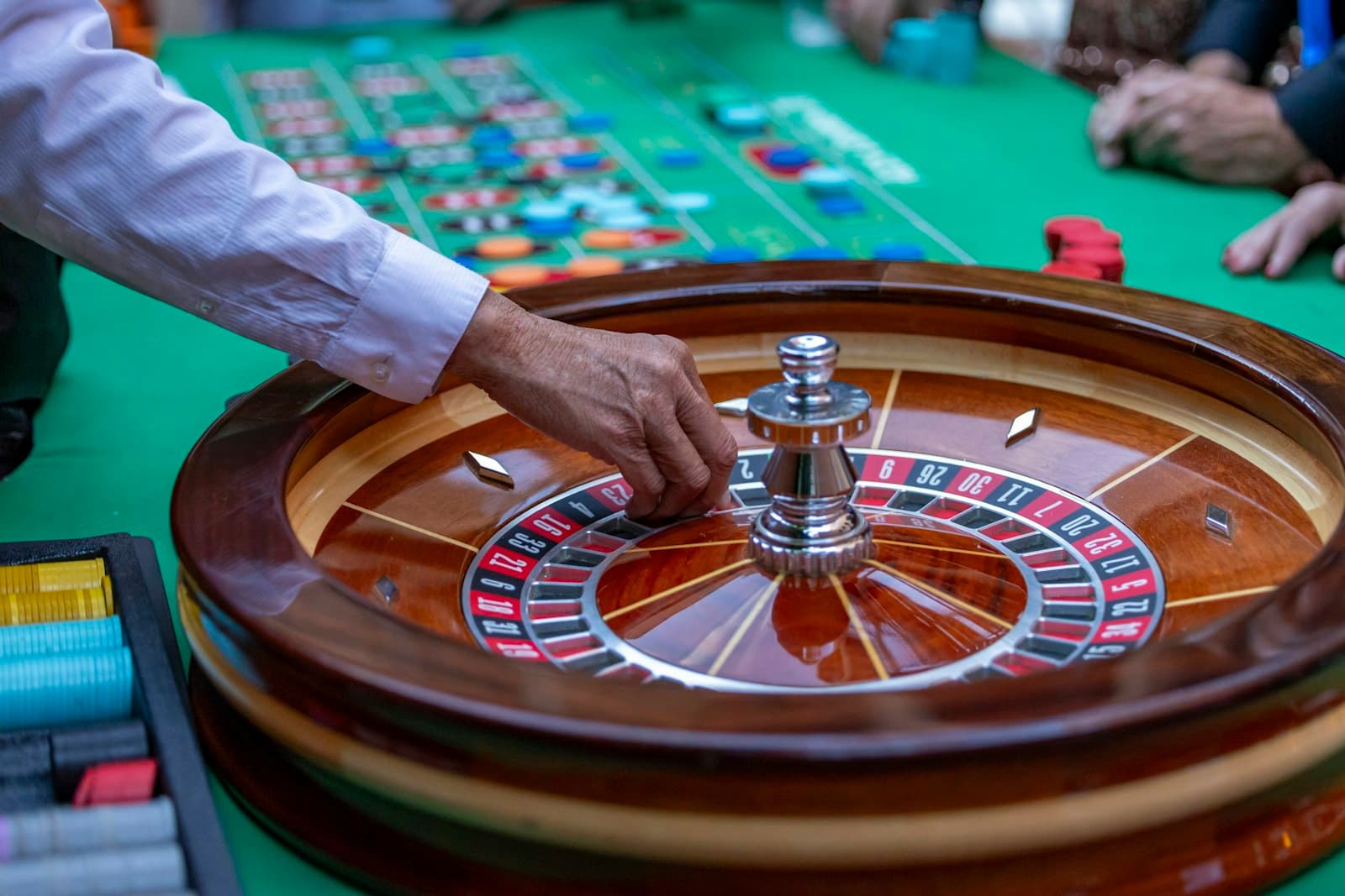 Dealer spinning a roulette wheel at a busy table